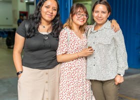Three friends posing happily together indoors, showcasing friendship and joy.